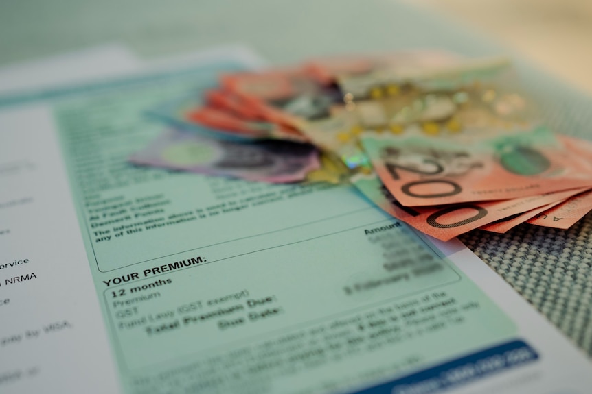 An up close of a fanned wad of cash, next to a greenslip document saying PREMIUM with blurred private details.