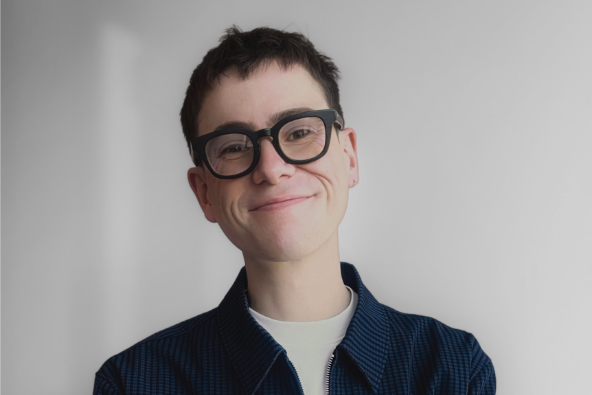 A young man with folded arms smiles at the camera.
