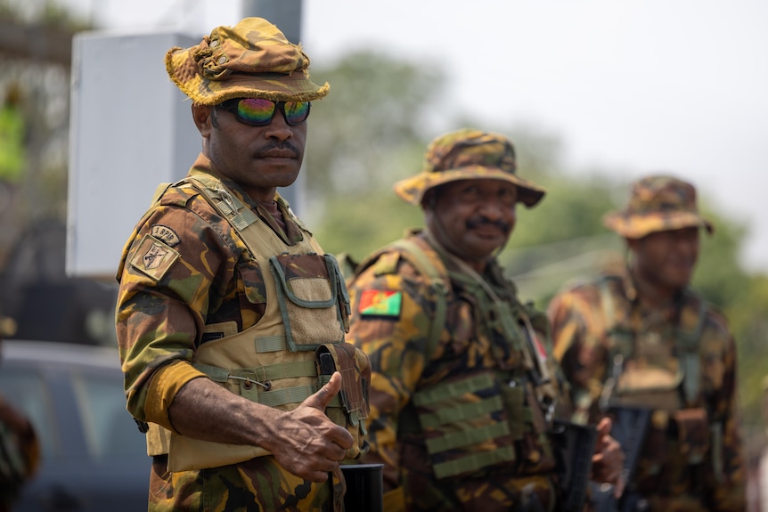 Three men in khaki military uniforms and floppy brim hats.