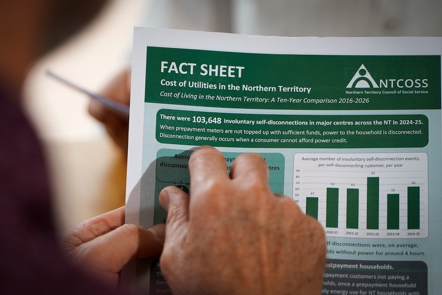 A man points to a fact sheet produced by NTCOSS as part of its cost of living report.