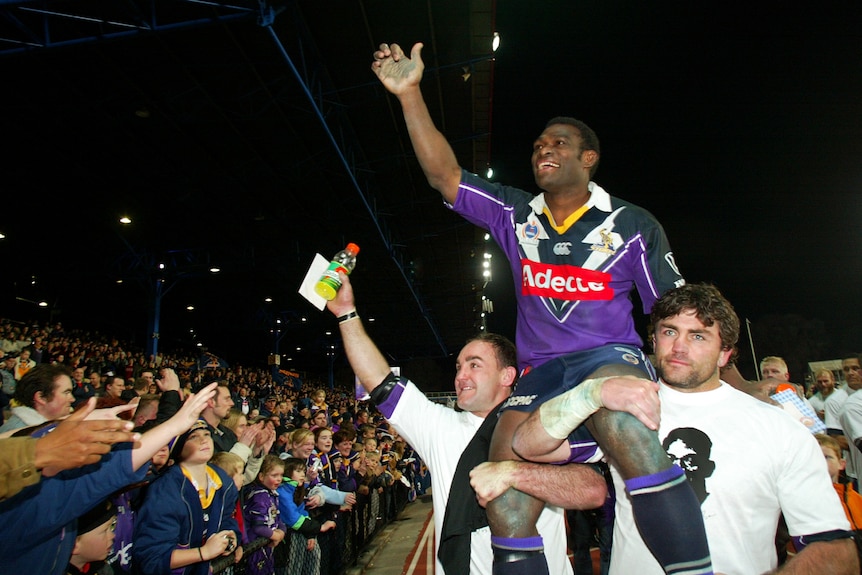 Marcus Bai waves to the crowd while being chaired off