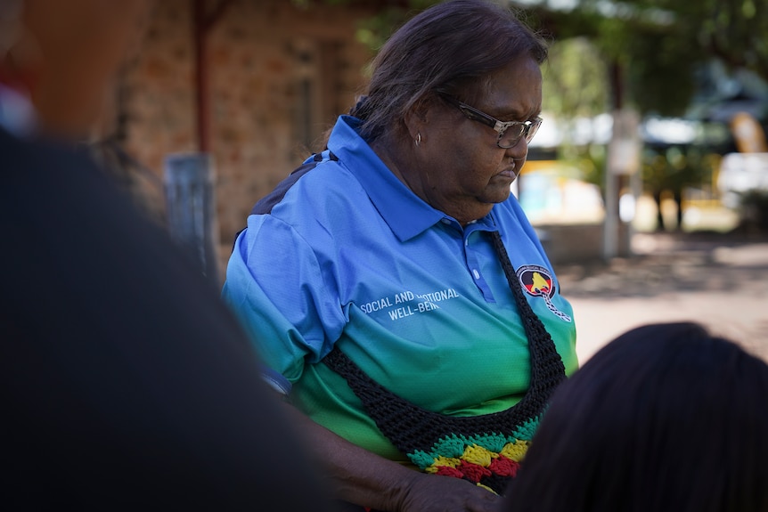 Shirley Miller looks down and to her left wearing a blue and green polo shirt.