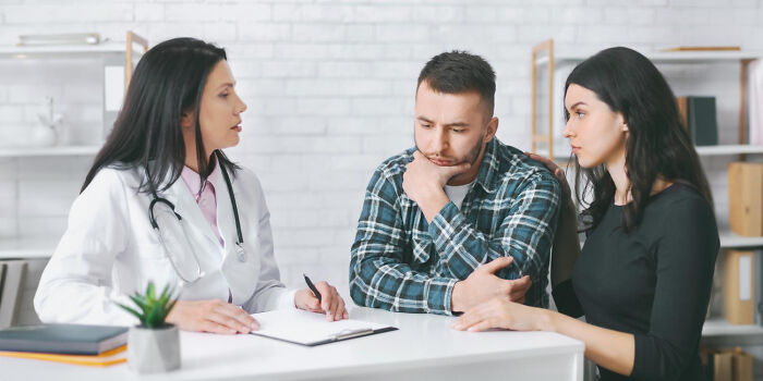A female doctor talking with a worried couple during a consultation with patients.