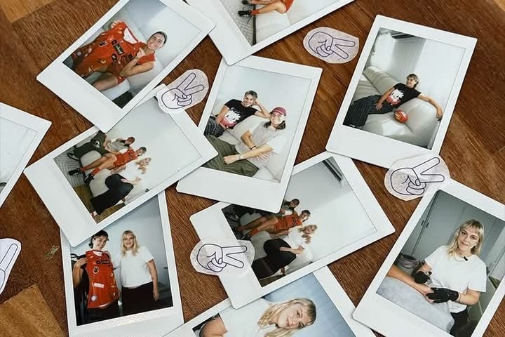 Polaroids scattered on a table of three different women smiling in various positions, as well as a number of tattoo stencils