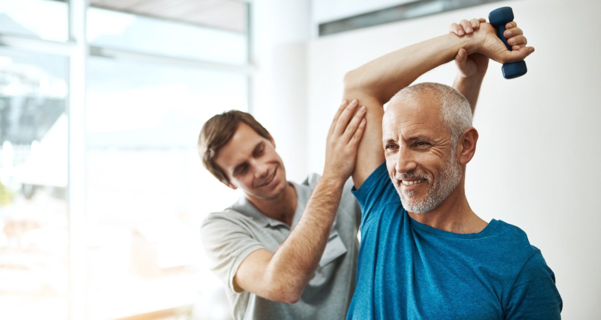 Strength, physiotherapist and mature man with dumbbell in clinic for physical therapy,