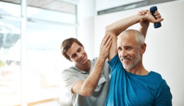 Strength, physiotherapist and mature man with dumbbell in clinic for physical therapy,
