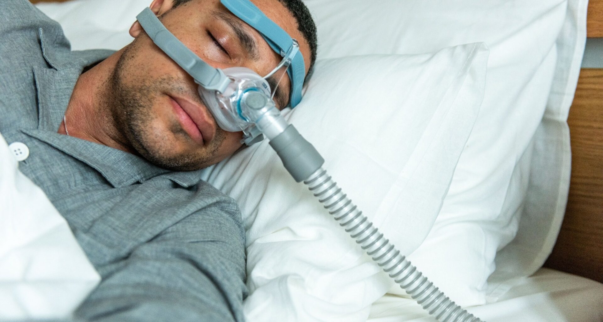 A person sleeps in bed wearing a CPAP mask for sleep apnea