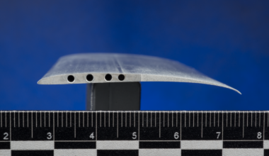 A close-up view of a cross-section of the Ingenuity rotor blade, also called an airfoil. The blade is shaped like an arched teardrop with holes drilled into the side.