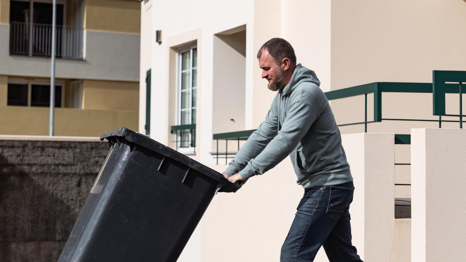 man pushing a trash can
