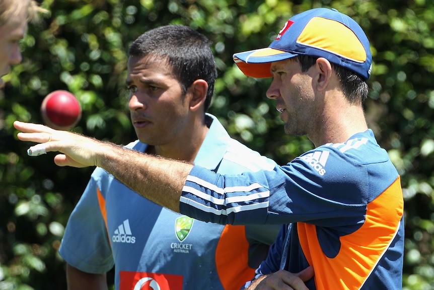 Usman Khawaja speaks with Ricky Ponting outdoors. Ponting is pointing.