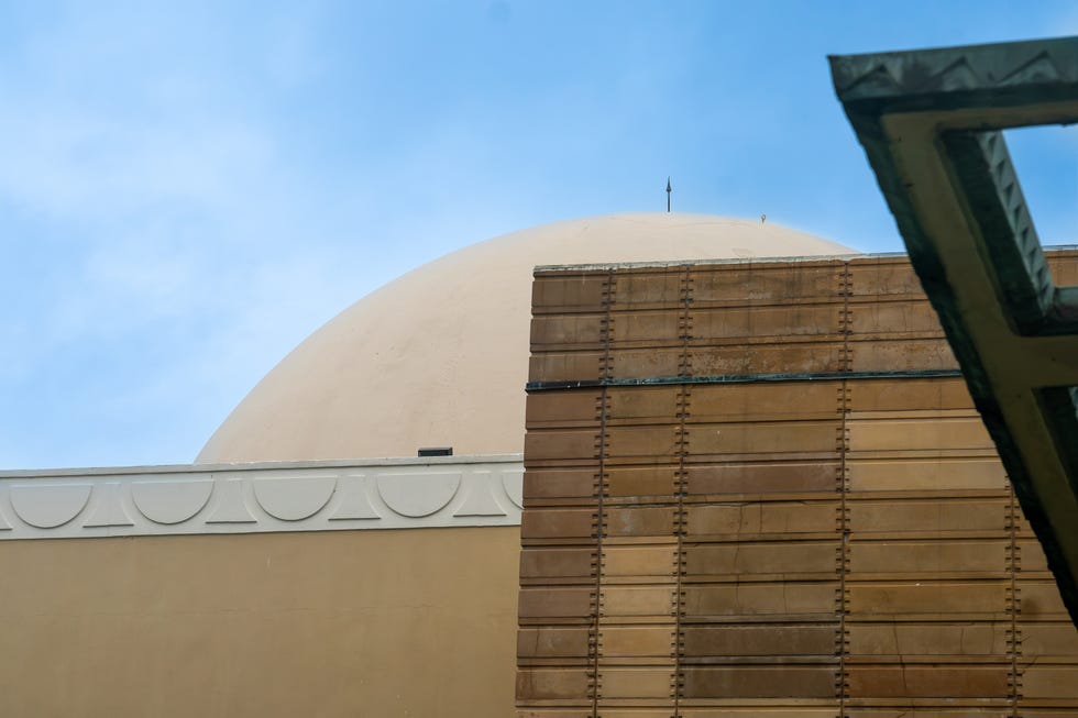 Architectural detail featuring a dome and textured wall against a blue sky.