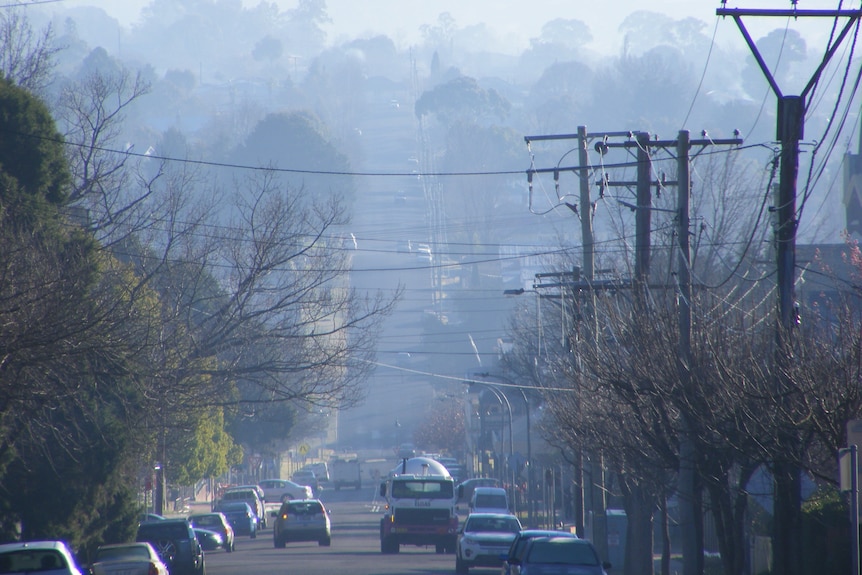 A streetscape with visible smoke hanging low over it.