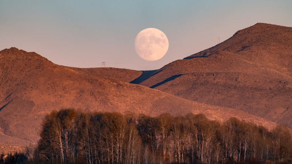 full moon rising over mountains
