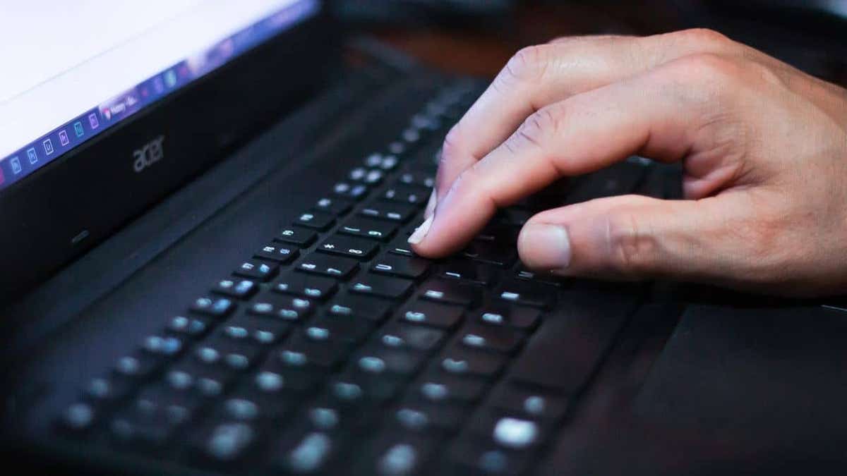 Close-up of a person typing on a black Acer laptop keyboard