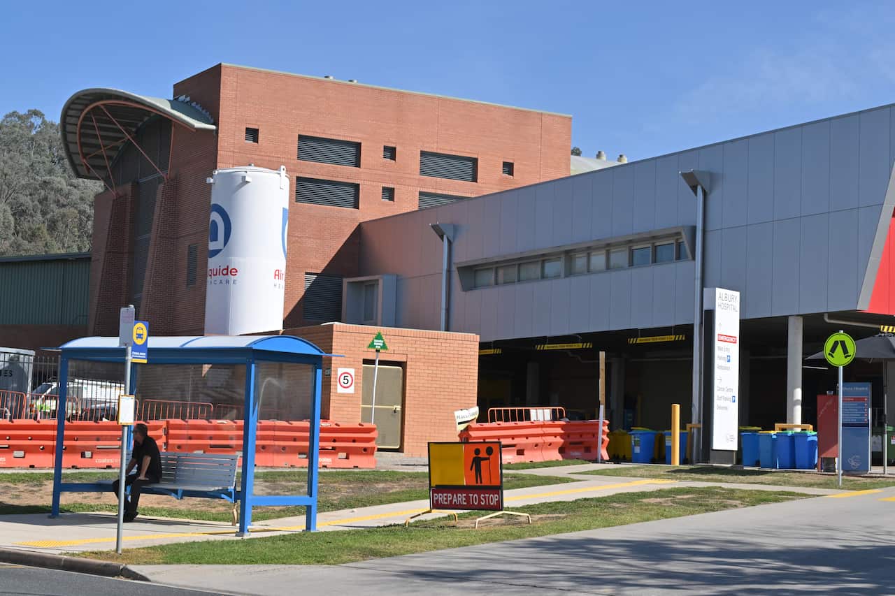 A hospital building with a bus stop in the foreground.