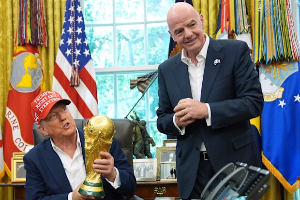 President Donald Trump holds the FIFA World Cup Winners Trophy as FIFA President Gianni Infantino looks on.