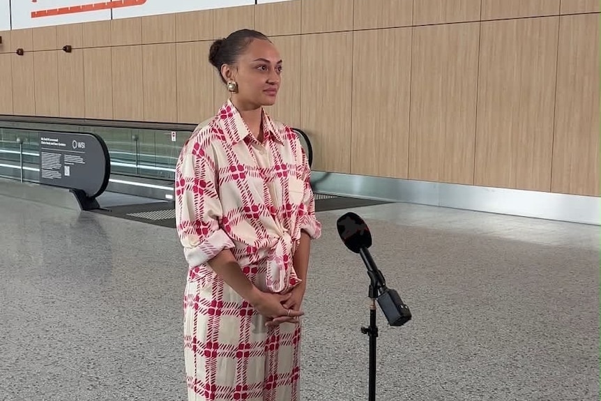A young woman speaks in an empty airport terminal.