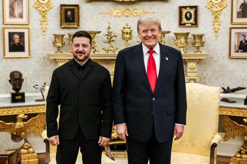 Volodymyr Zelenskyy and Donald Trump stand side by side and smile in the Oval Office.