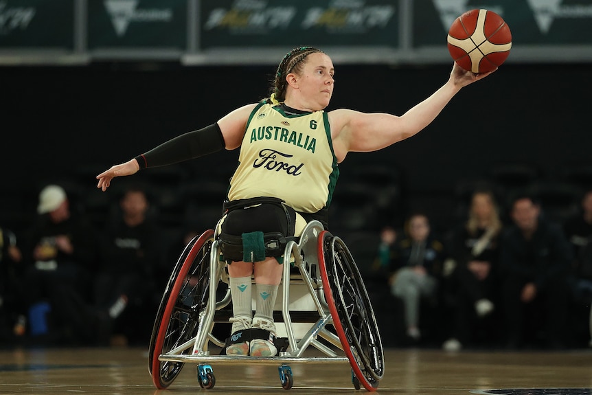 Hannah Dodd gliding in her wheelchair and catching the basketball.