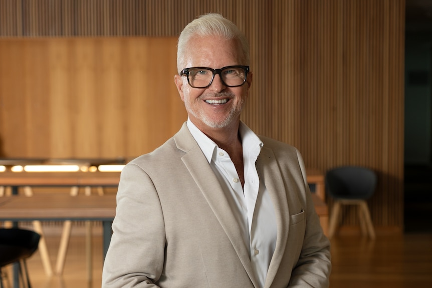 A man in a suit smiles at the camera.