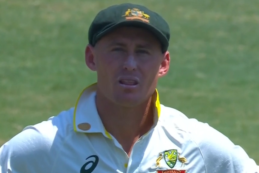 A close up shot of a cricketer in a baggy green looking unimpressed.