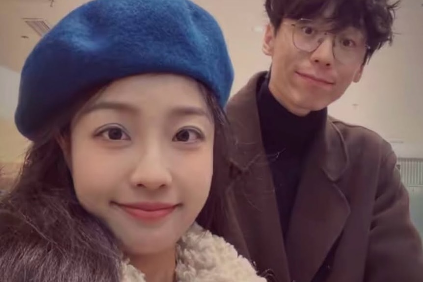 A young couple, with the woman wearing a beret and warm coat, taking a selfie.