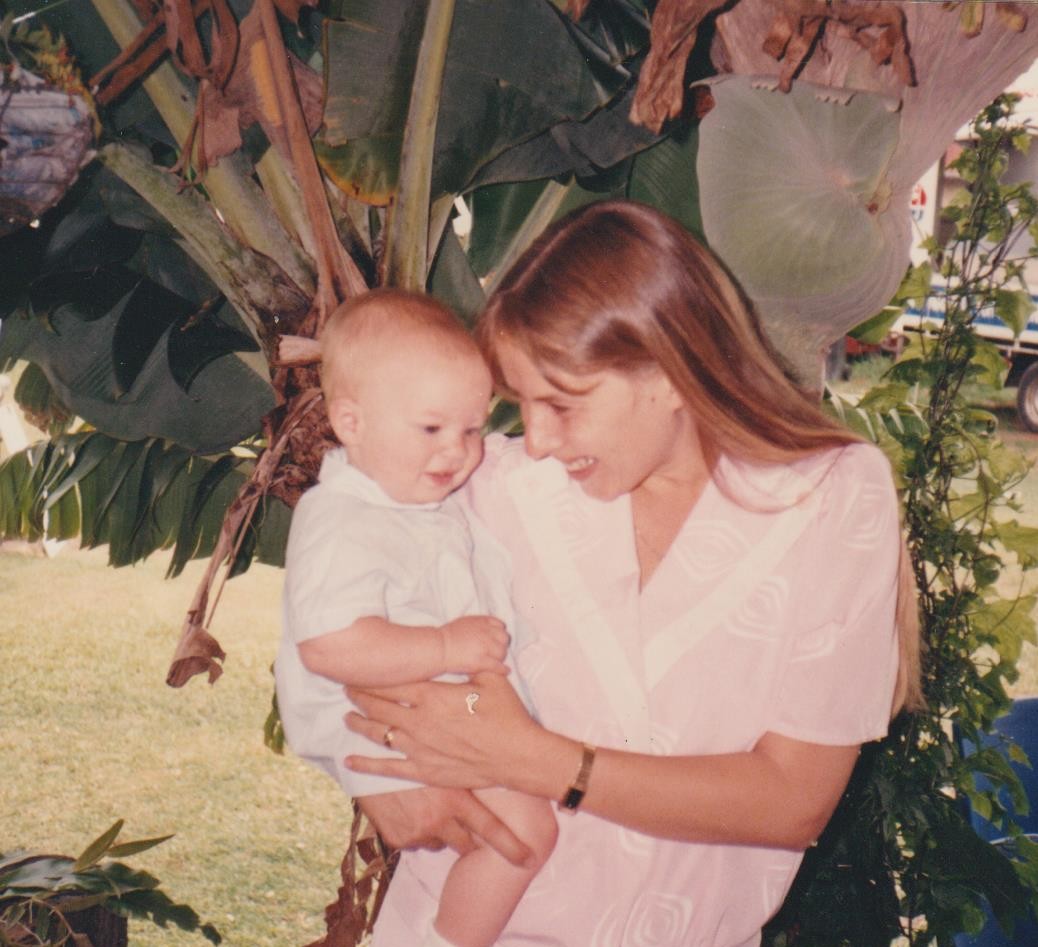An old photo of a long-haired woman holding a baby in her arms
