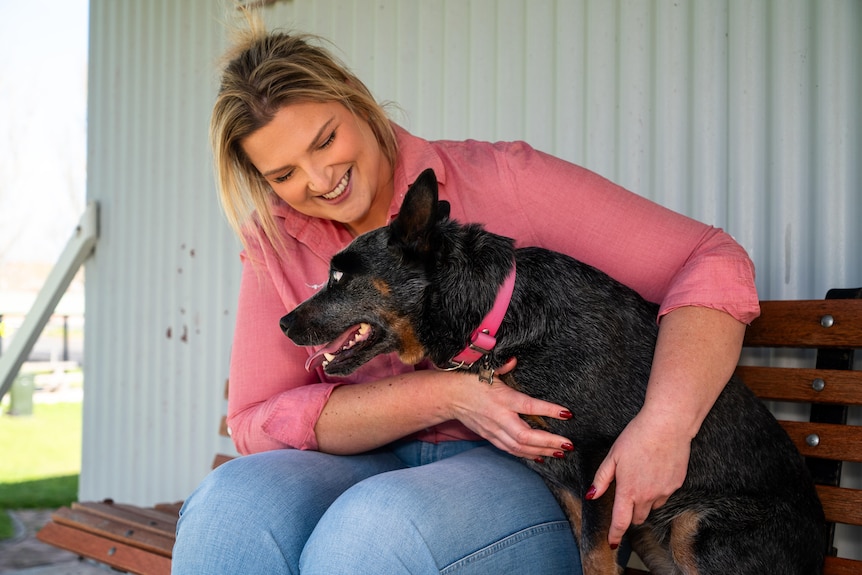a woman sitting on a park bench smiling and patting her dog