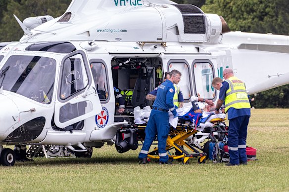 Paramedics prepare to transport a patient by helicopter after 10 people, who had gathered to farewell the Newcastle Knights team bus, were injured by a car driving into the crowd.