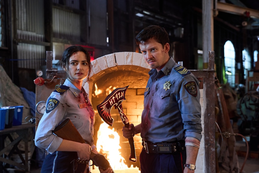 two police officers stand in front of a lit furnace
