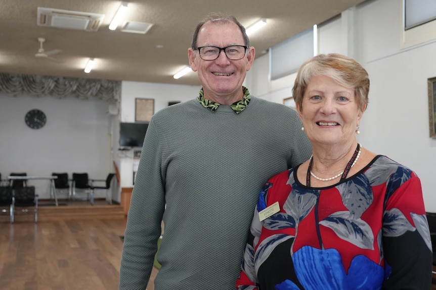 A smiling older couple in a public hall.