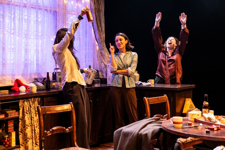 On stage, Mabel Li, Emma Diaz and Ariadne Sgouros, three young women, celebrate, Li and Sgouros's arms in the air.