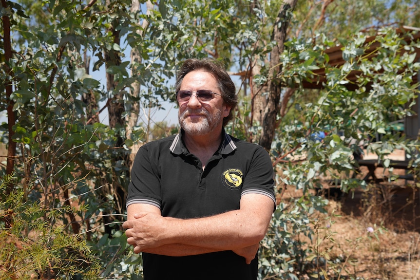 A man in black shirt posed in front of a tree