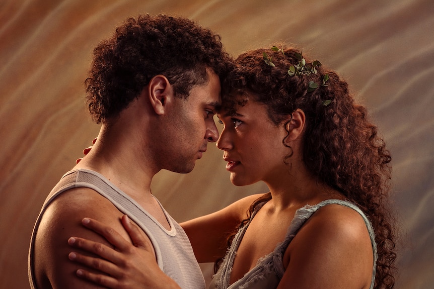 Likiki Millett and Ruby Henaway, an Indigenous young man and woman, touch foreheads, looking into each other's eyes.