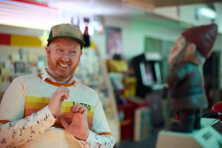 A man cringes towards a gnome in a video store
