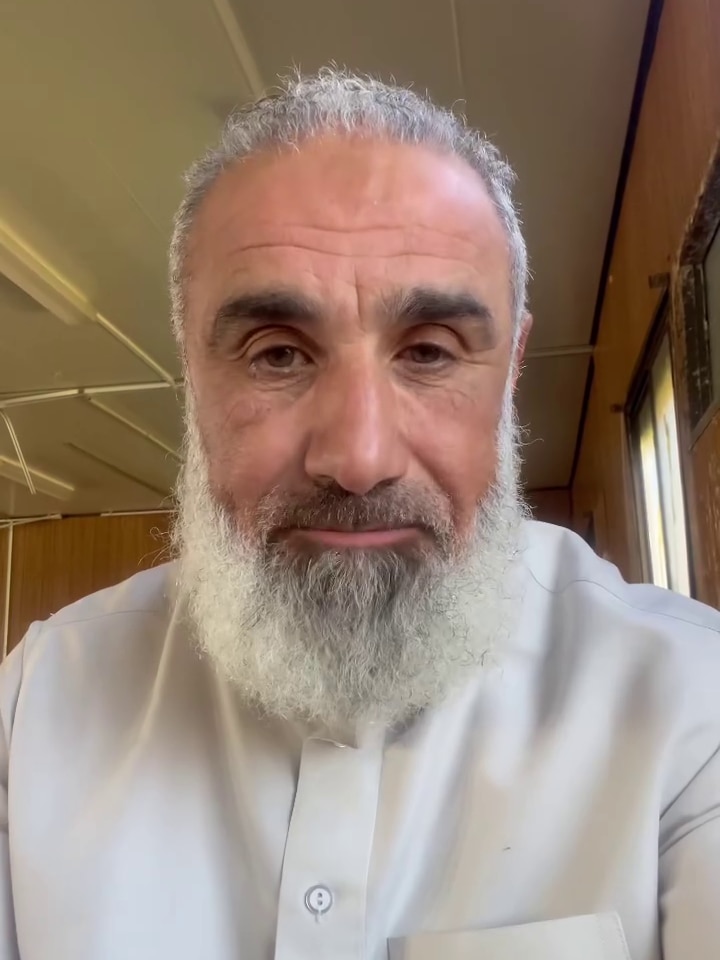 A bearded man looks into a phone selfie camera.