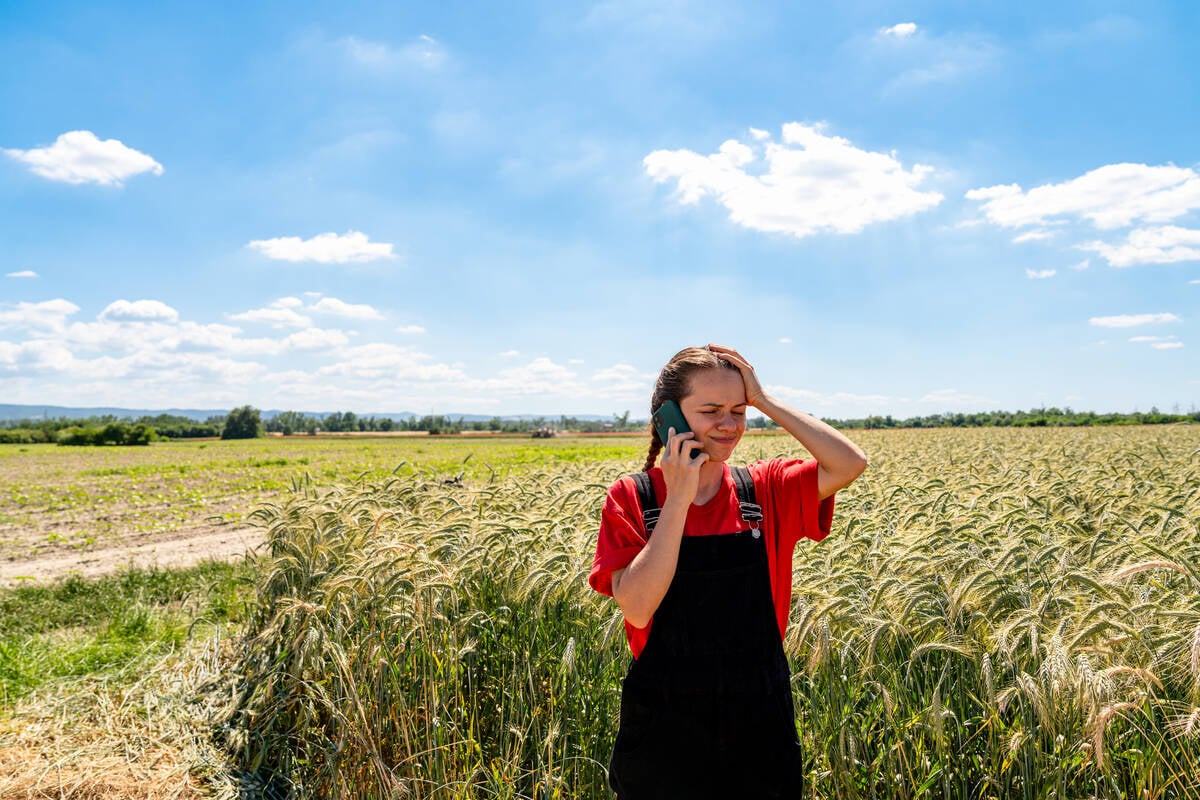 Female farmer receiving bad news during phone call by cereal field
