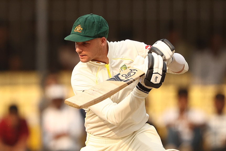 Peter Handscomb in cricket whites holds his bat across his body.