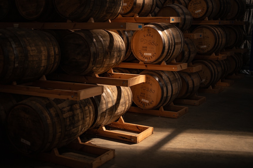 Dusty barrels and a warm coloured copper still in large shed