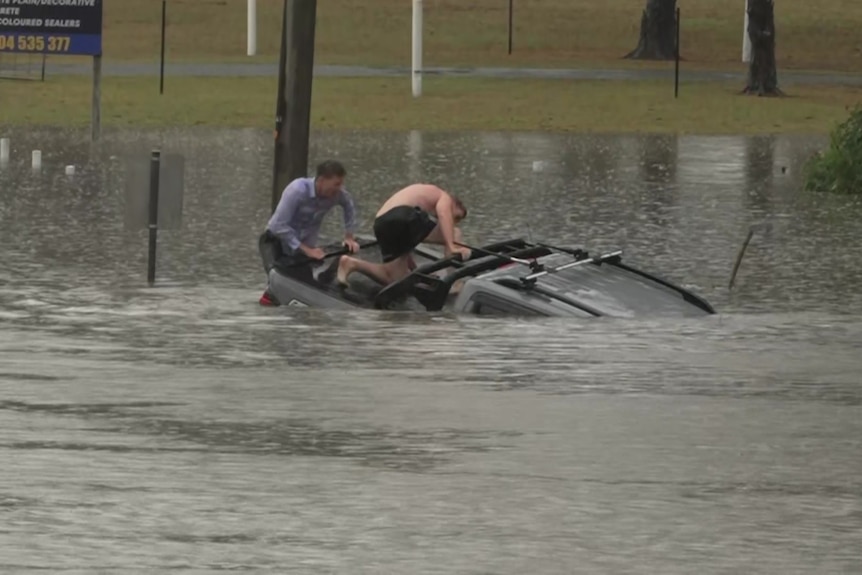 ABC reporter Will Murray and another man pull a man from a sinking car.