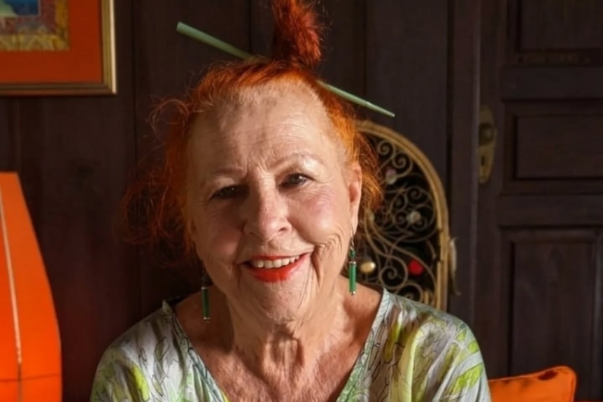 A middle-aged woman with red hair smiles while posing for a portrait.