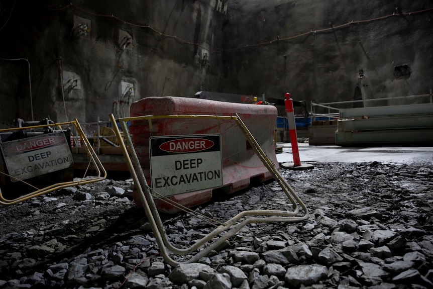 A safety warning in an underground tunnel with rocks.