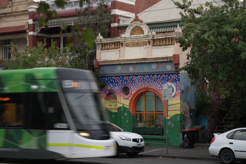 A tram passing an inner-city building with a rainbow facade.