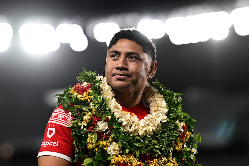 Tongan rugby league player Jason Taumalolo, wearing wreaths around his neck, looks to the stands after a game.