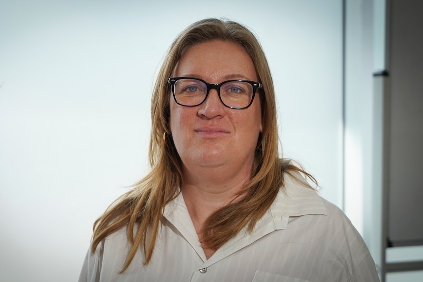 Claire Pirrett looks directly at the camera wearing black-rimmed spectacles and a white blouse.