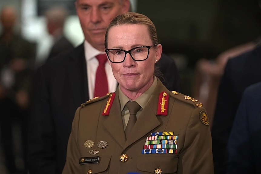 Chief of Army Lieutenant General Susan Coyle in her uniform with closed lips and Richard Marles behind her