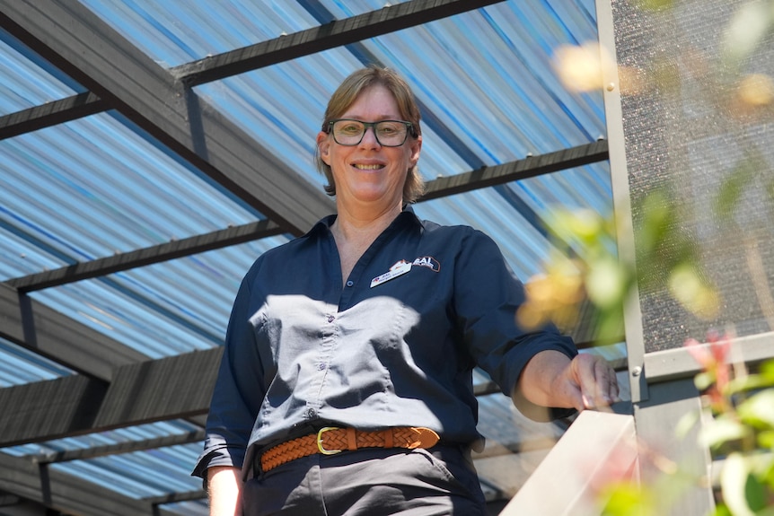 A woman stands under a backyard covered area.