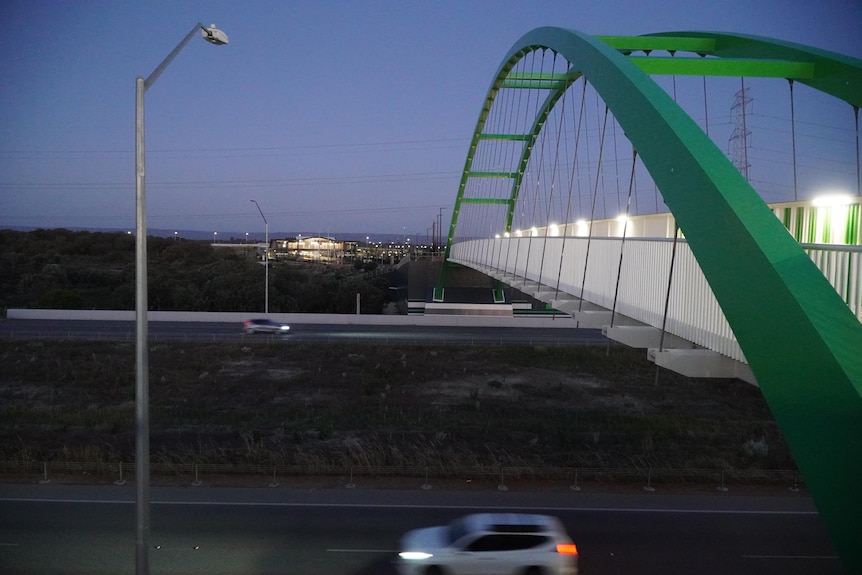 Two cars drive along a road without streetlights.