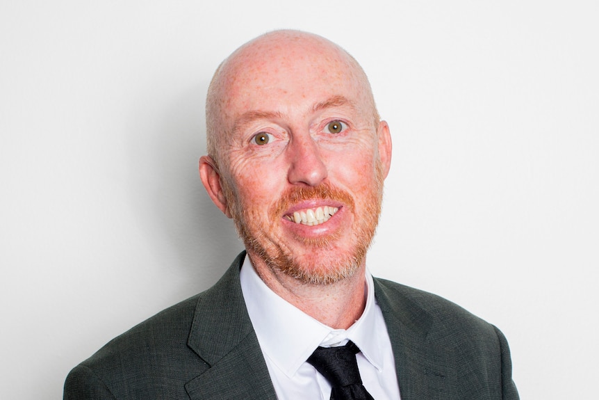 Man in suit smiles at the camera