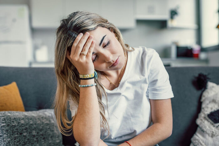 Exhausted woman resting her head on her hand on a couch, feeling sick and tired
